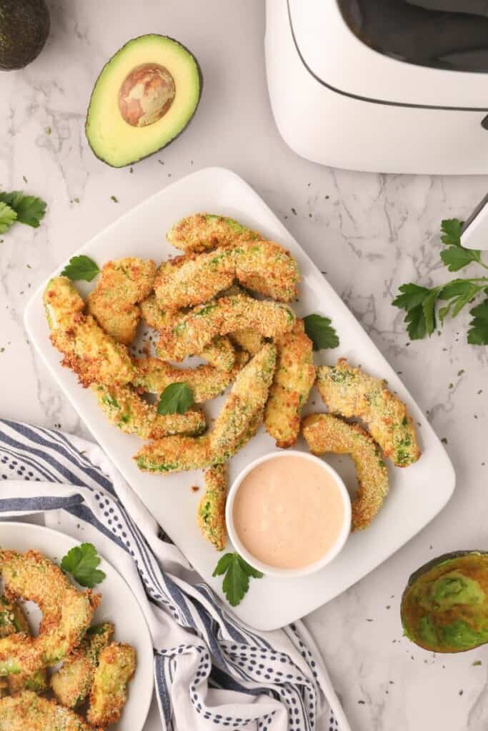 Overhead view of air fryer avocado fries on plate with sauce