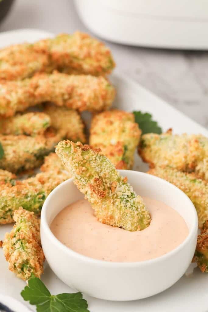 Avocado fry being dipped in sriracha ranch sauce