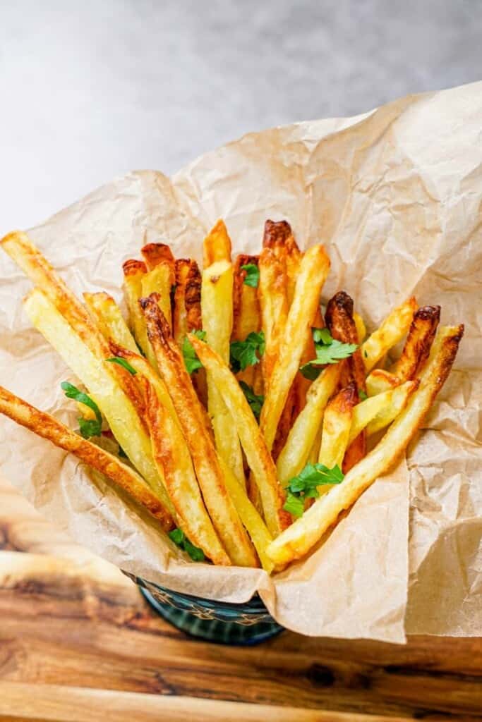 cooked french fries in a bowl with parchment paper