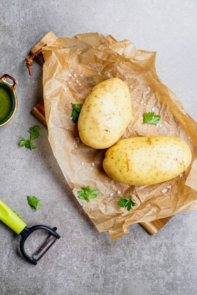 Potatoes on parchment paper with a y peeler
