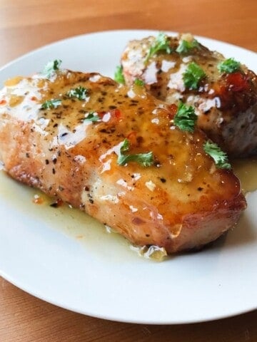 Air Fryer Pork Chops coated in honey garlic sauce on a white plate