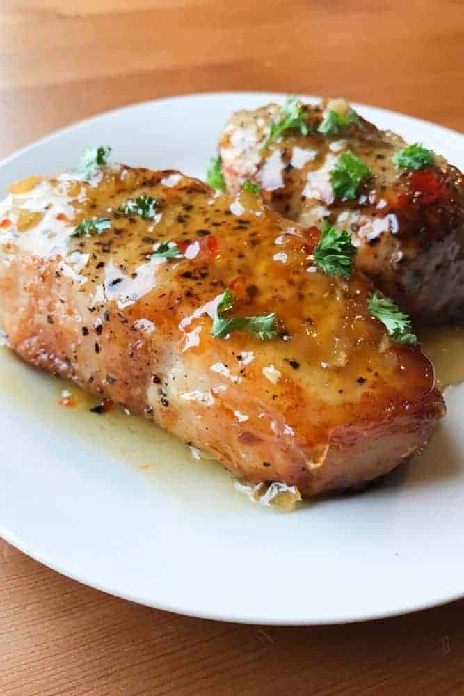 Air Fryer Pork Chops coated in honey garlic sauce on a white plate