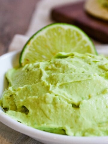 Avocado Crema in white bowl with lime wedge