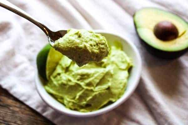 Avocado Dip in a white bowl and a spoonful of it over top.