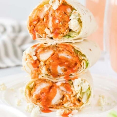 3 Buffalo chicken wraps stacked on top of each other cut in half on a white plate