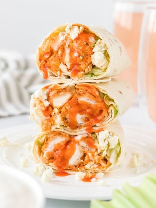 3 Buffalo chicken wraps stacked on top of each other cut in half on a white plate