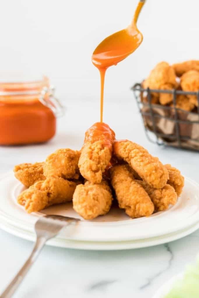 Wamred buffalo sauce being drizzled on top of chicken