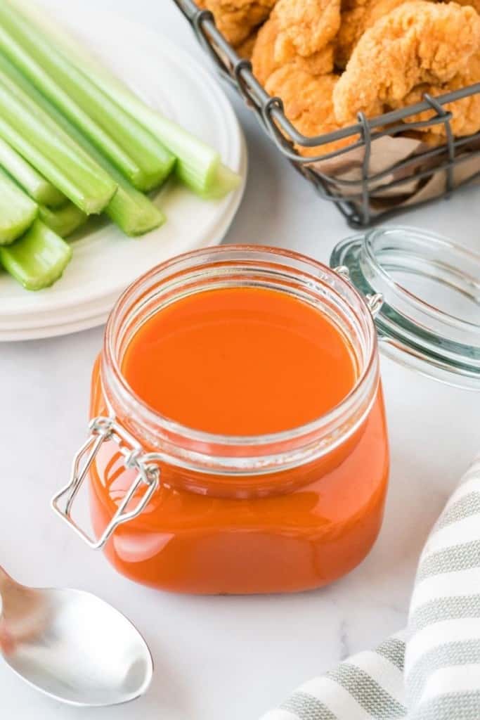 Buffalo sauce inside a mason jar served with celery and chicken