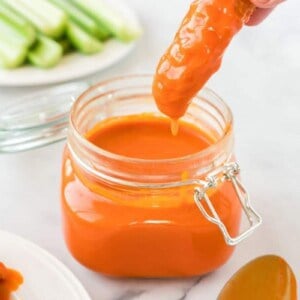 Homemade Buffalo Sauce in a mason jar with chicken tender being dipped in them