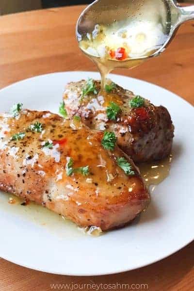 Honey garlic sauce being poured on pork chops with a spoon