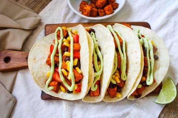 Assembled Sweet Potato Tacos on a small brown cutting board