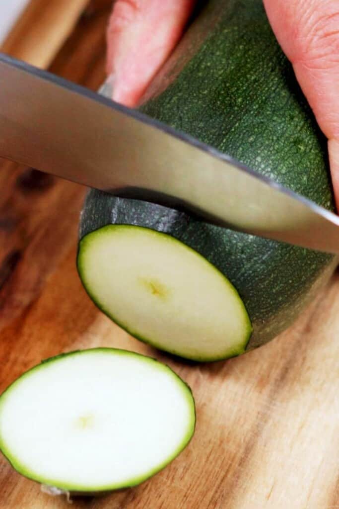 Zucchini being sliced with a knife