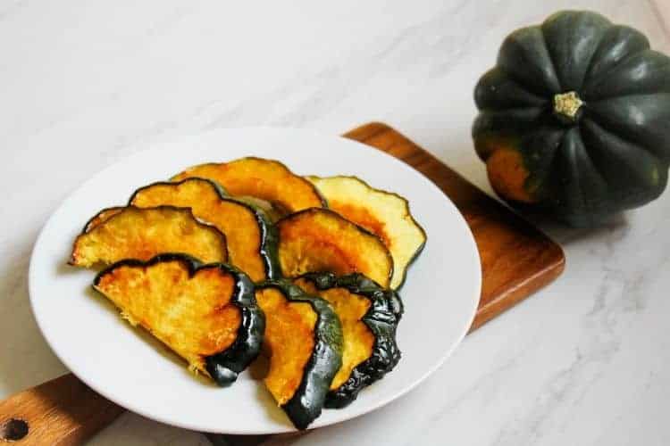 Air Fryer Slices on a white plate with whole acorn squash in background