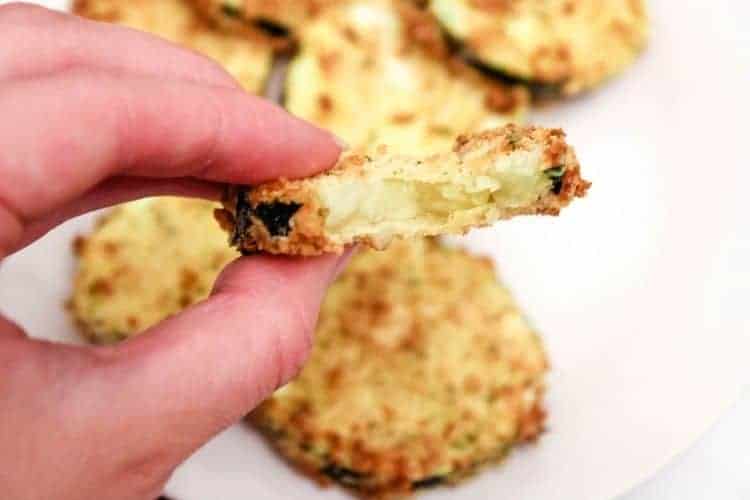 Hand holding Air Fryer Zucchini Chips with bite taken out of it