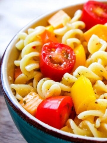 Italian Pasta Salad in blue bowl with tomatoes, peppers, and cheese