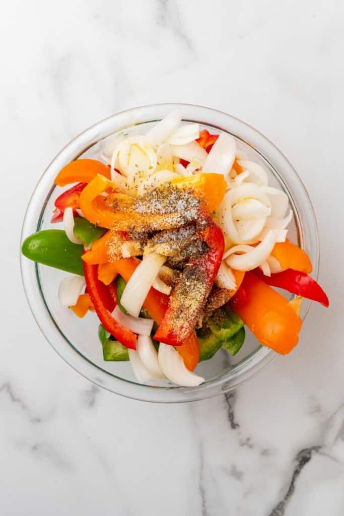 Peppers, onions, and seasonings in a glass bowl