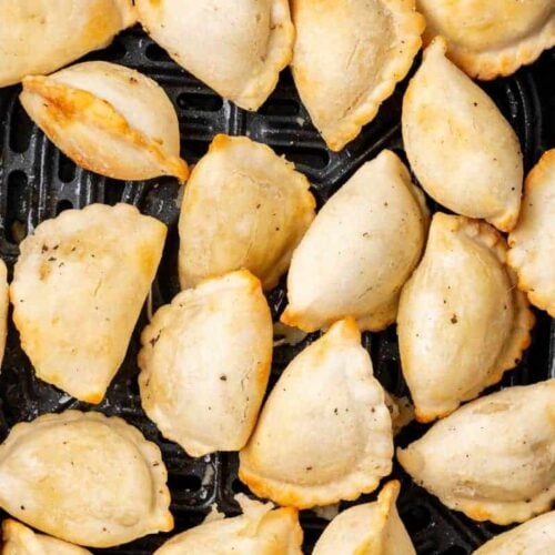 golden brown pierogies in an air fryer basket