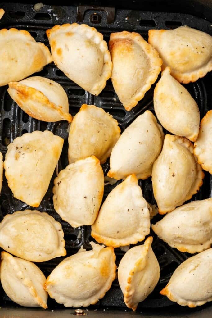 golden brown pierogies in an air fryer basket