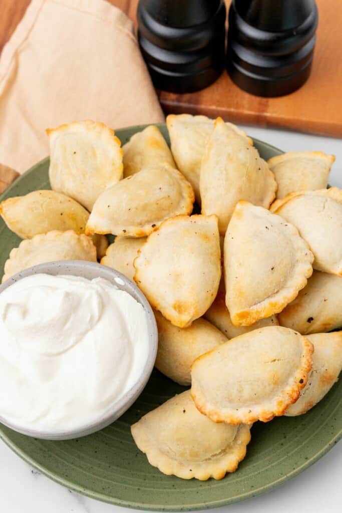 cooked air fryer pierogies on a plate with sour cream