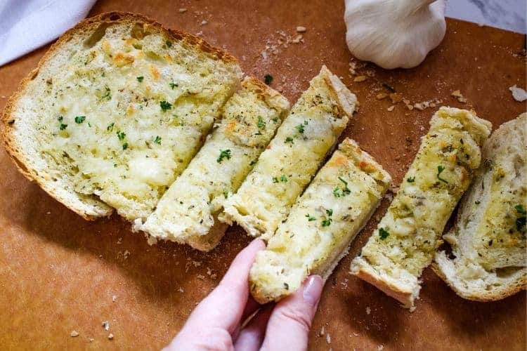 Hand grabbing sliced Garlic Cheese Bread