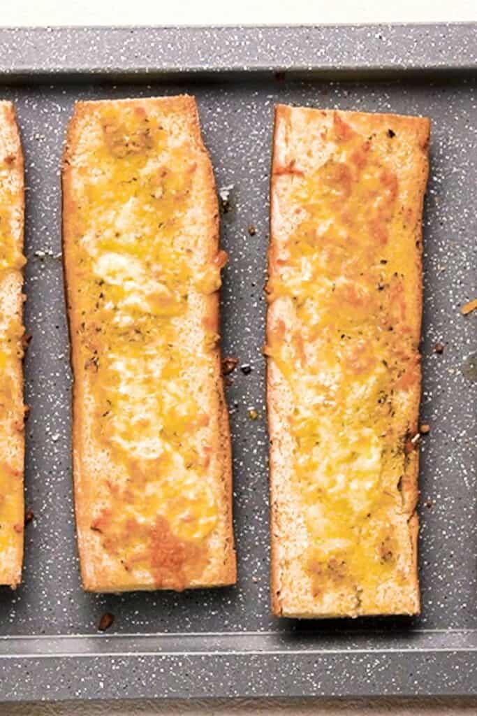 Cooked cheesy garlic bread on a baking sheet