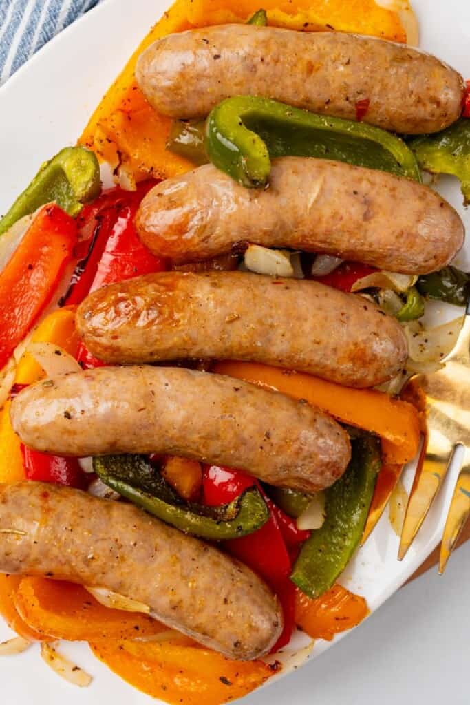Italian sausages on top of cooked peppers and onions on a plate
