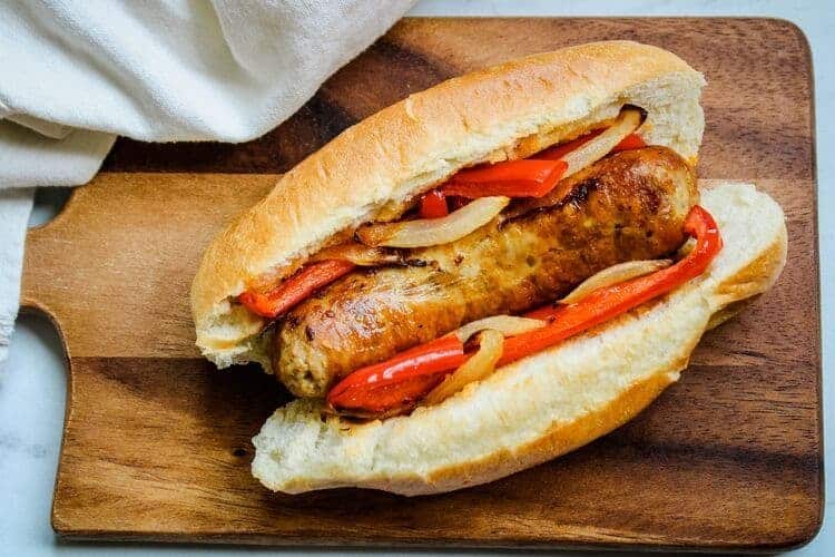 Air Fryer Italian Sausage Sandwich with peppers and onions on cutting board