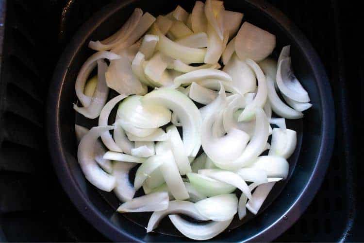Raw sliced onions inside air fryer on air fryer pan