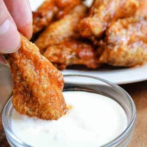 Air Fryer chicken wing being dipped in bowl of blue cheese