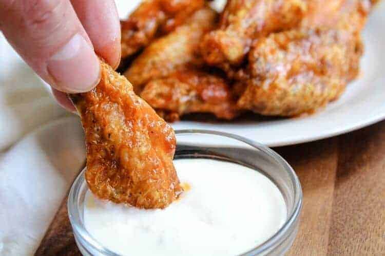 Air Fryer chicken wing being dipped in bowl of blue cheese