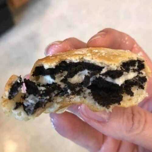 Hand holding an air fryer oreos that has been bitten into so you can see the oreo in the middle.