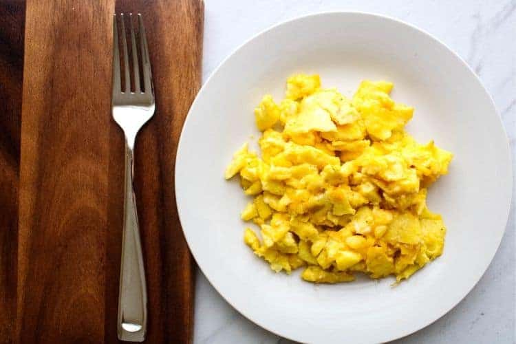 Scrambled Eggs on a white plate with fork to the side