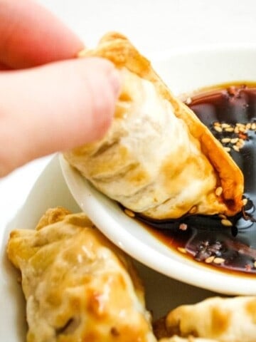 Dipping Air Fryer Dumpling in Sauce on a white plate