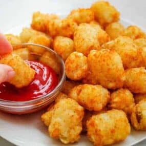 Air Fryer Tater Tots with one being dipped in ketchup