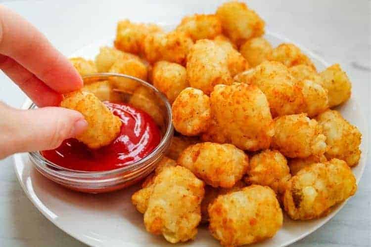 Air Fryer Tater Tots with one being dipped in ketchup