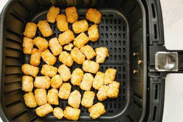 Tater Tots in air fryer basket from overhead view.