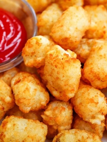 Closeup of Air Fryer Tater Tots with bowl of ketchup peaking into the top left