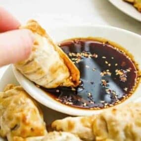 Dipping Air Fryer Dumpling in Sauce on a white plate