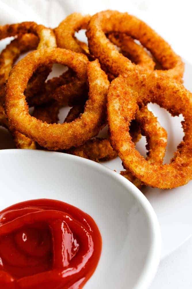 Onion Rings on a white plate with ketchup in front