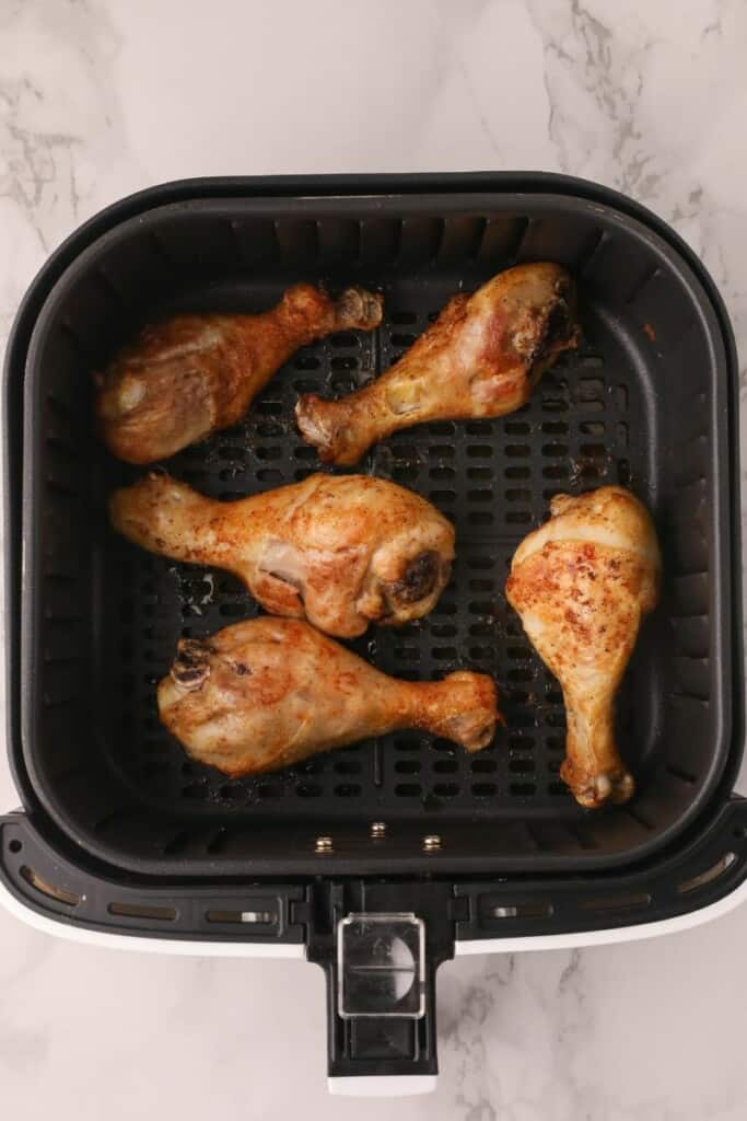 Half cooked chicken legs in the air fryer