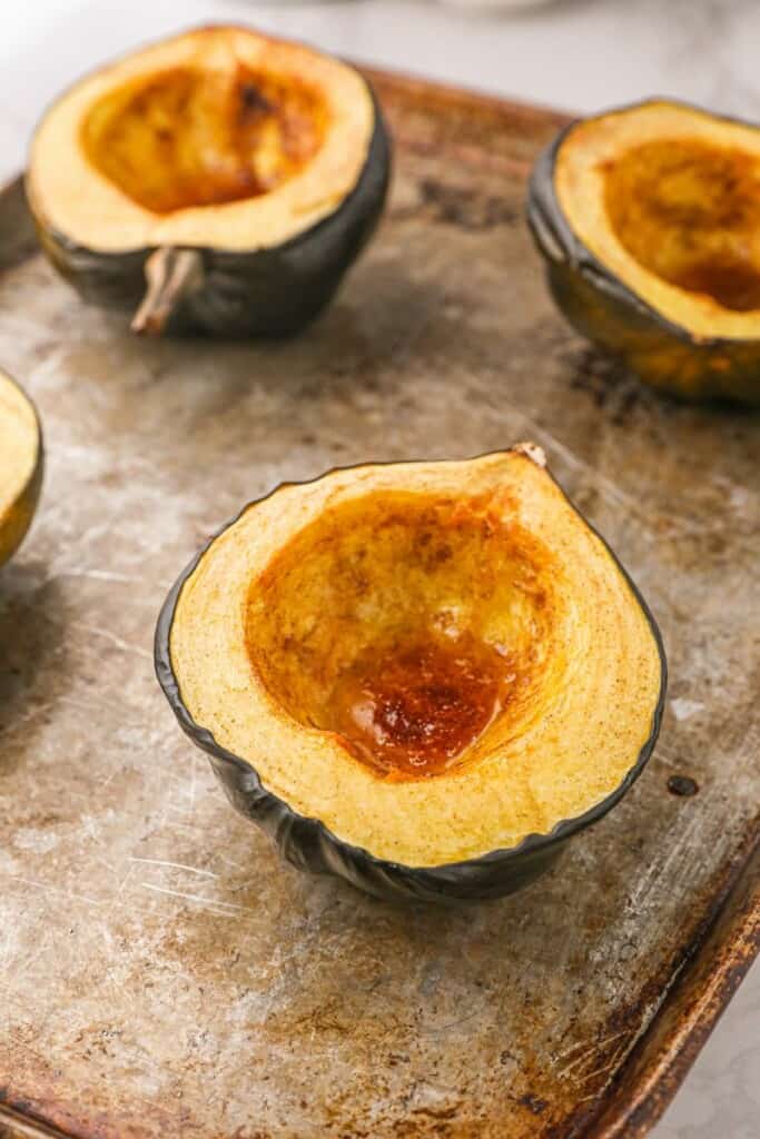 Cooked acorn squash halves on baking sheet