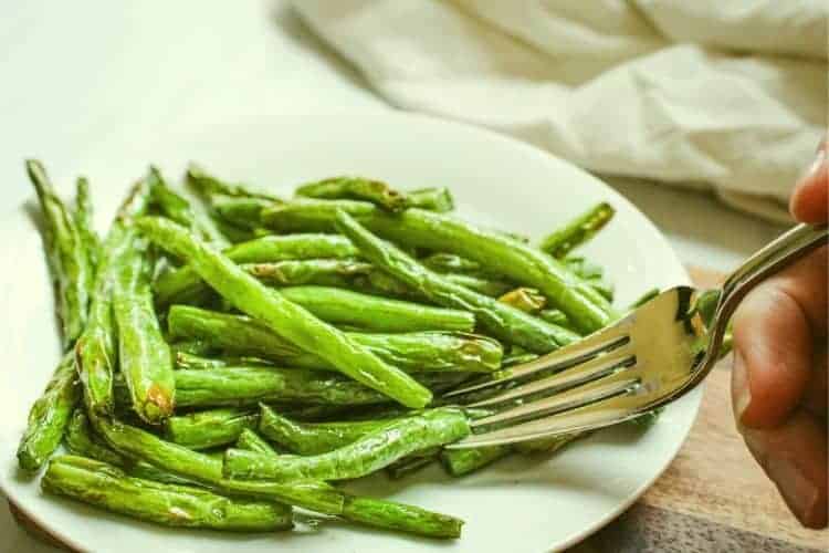 Air Fryer Green Beans on a white plate with fork in it