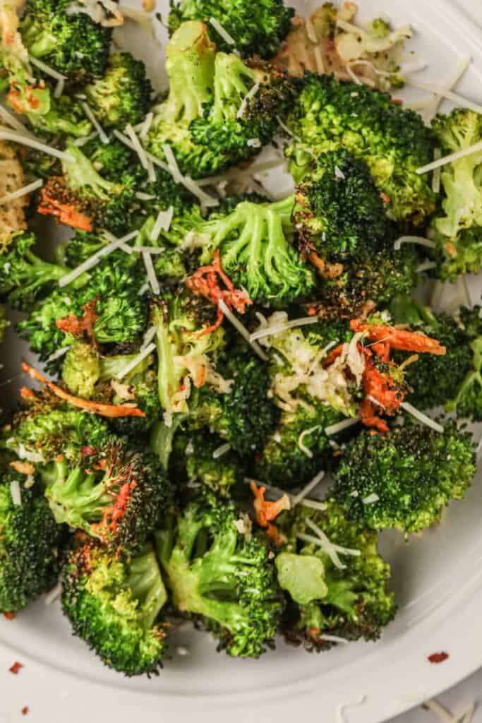 Air fried broccoli on a white plate with parmesan on top