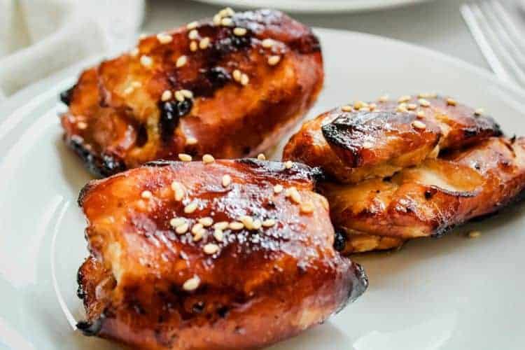 Honey Soy Air Fryer Chicken Thighs topped with sesame seeds on a white plate