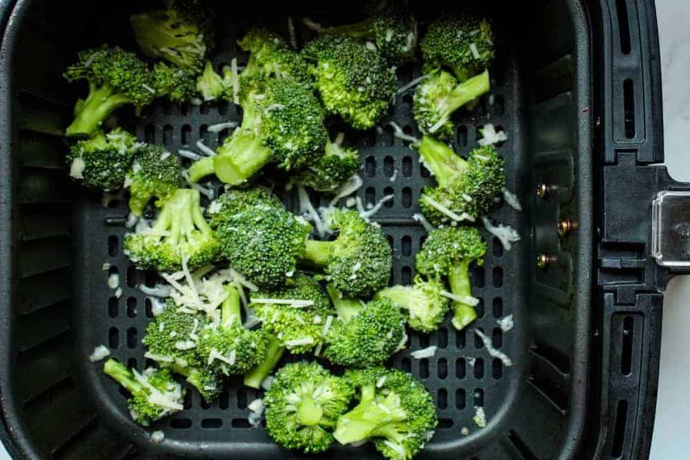 Raw broccoli with parmesan cheese inside air fryer