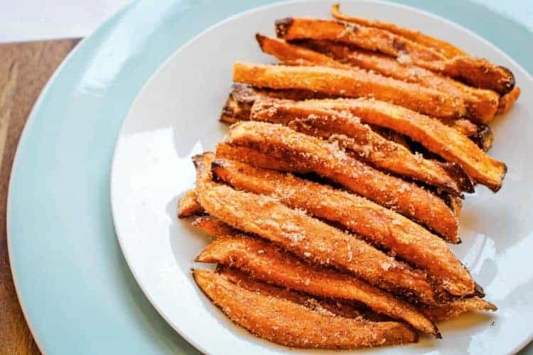 Sweet Potato Cinnamon Sugar Fries on a white plate with blue charger plate underneath