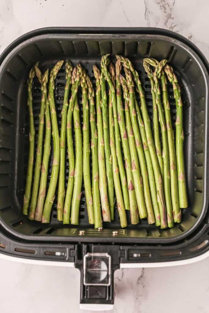 Raw asparagus in air fryer basket