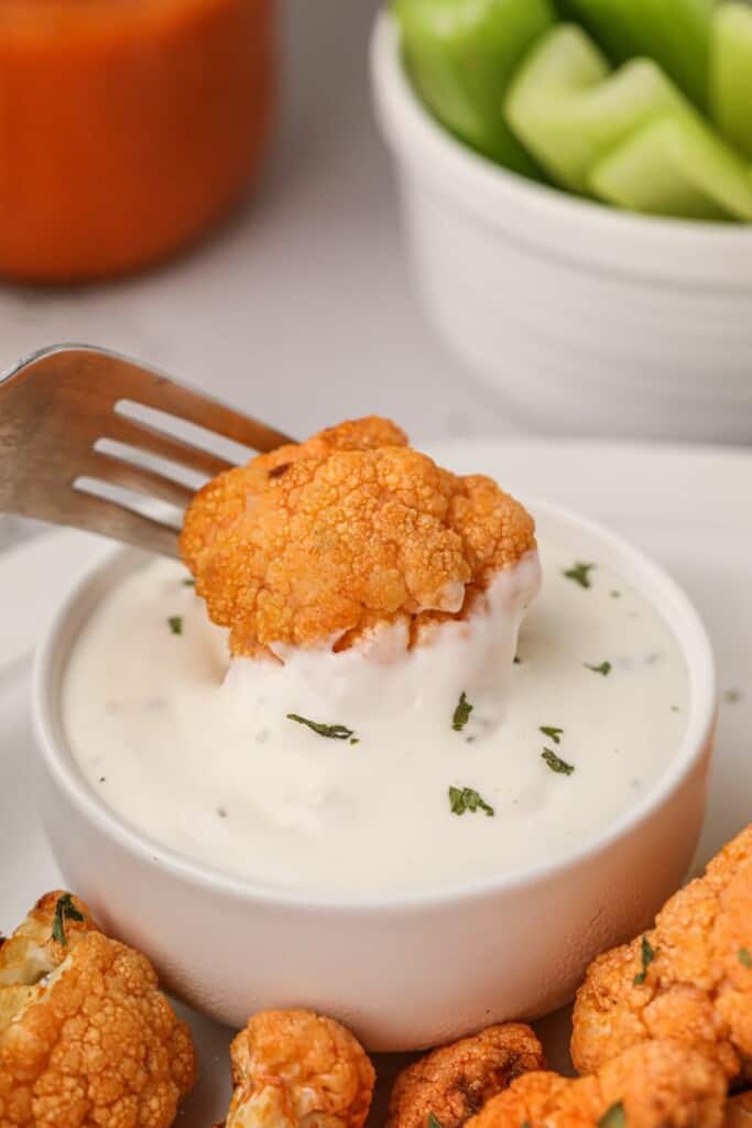 Buffalo cauliflower being dipped in blue cheese