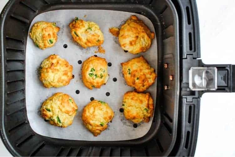 Cooked hushpuppies inside air fryer with parchment paper