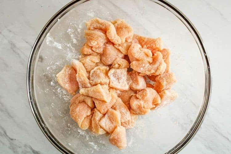 Cubed chicken covered with cornstarch in clear bowl